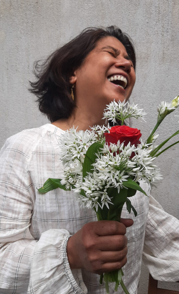 female gardener laughing clutching boquet of wild flowers